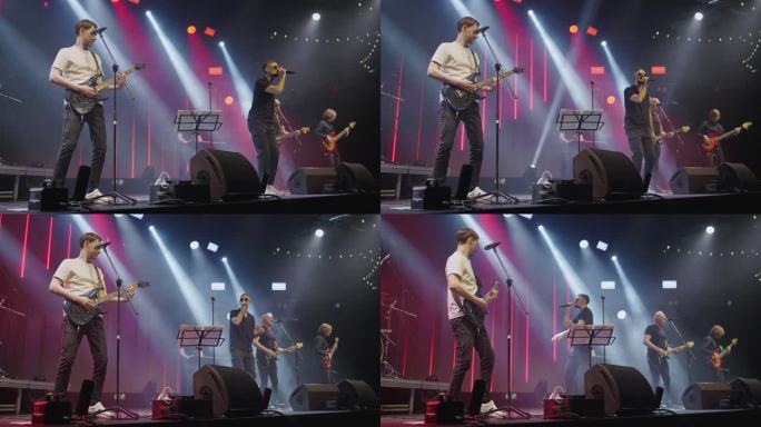 现代流行乐队主唱吉他手和键盘手在夜总会的舞台上表演。慢动作