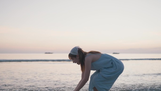 夕阳下漫步在海边的迷人女子。