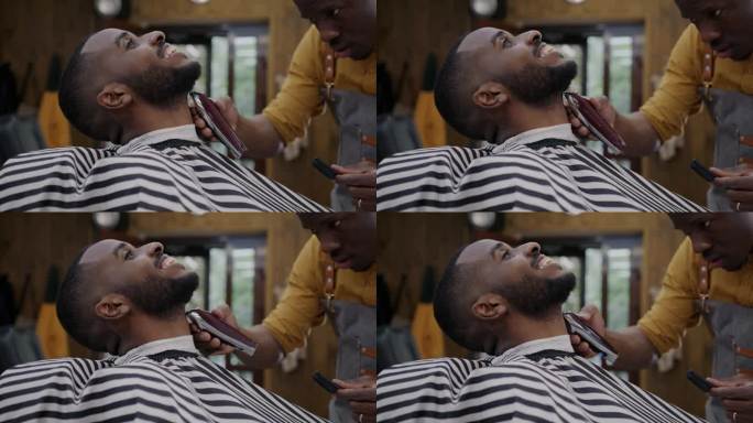现代理发店里，技艺精湛的美发师用剃须机给一个英俊的非裔美国人剃须