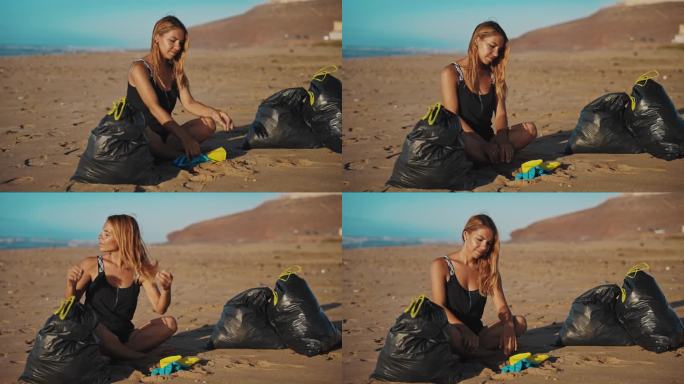 金发女郎坐在沙滩上，旁边有很多垃圾袋，她刚从沙滩上收集完垃圾