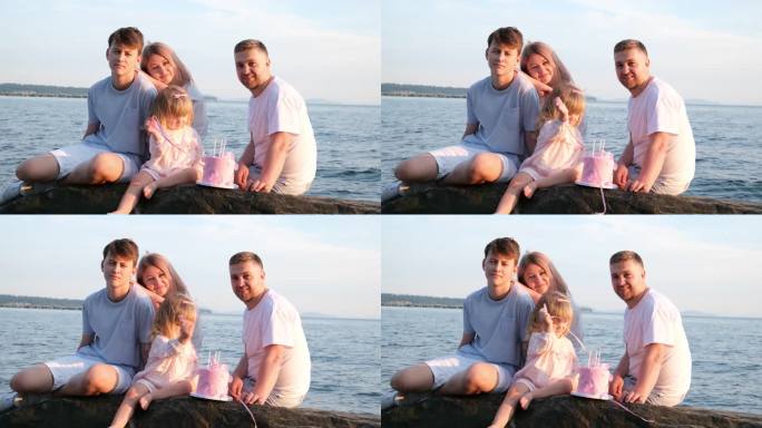 全家人都看着相框妈妈躺在儿子爸爸哥哥和小妹妹的肩膀上谁是玩丝带3年蛋糕粉红色生日海滩美女爱家庭幸福宝