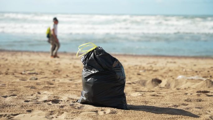 黑色垃圾袋完全装满垃圾站在沙滩上