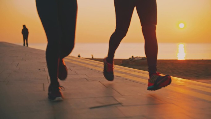 女性朋友在散步道上慢跑的照片。日出时大海田园诗般的景色。他们在黎明时分锻炼身体