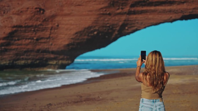 一名女子在海滩上用手机捕捉到令人惊叹的岩层