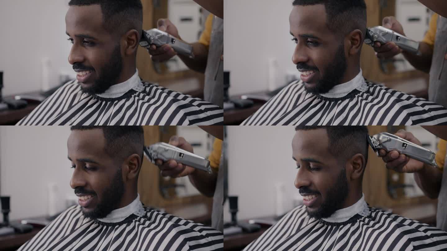 理发师用电动机器给他剃头时，一名非洲裔美国人微笑的特写