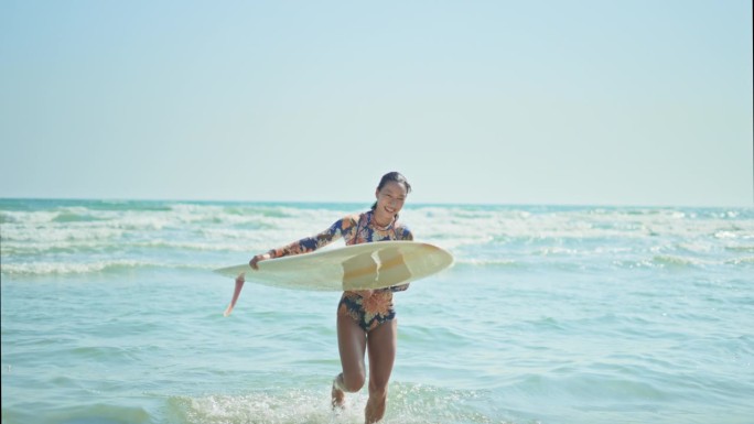 女冲浪者带着长板离开海浪，慢镜头