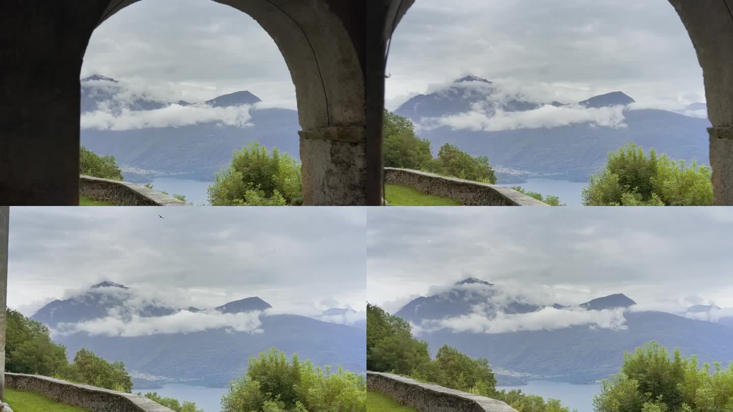 一座古建筑拱门后，云雾缭绕的山脉向外延伸