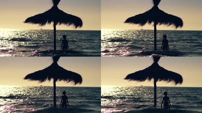迷人的女人穿着比基尼站在草冠伞下在浅海在日落的海滩。度假和热带夏季。慢动作