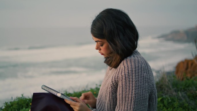 专注的女孩画素描坐在岸边与相册的特写。女性绘画。