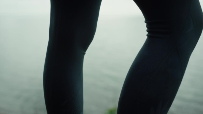 运动员的腿站在海滩山特写。坚强的女孩的脚踩在干草地上。