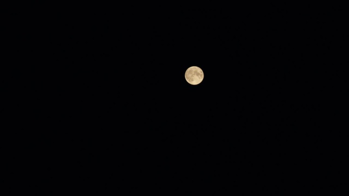 从地球上看到的金色满月。满月穿过大气层，映衬着繁星点点的夜空。间隔拍摄。