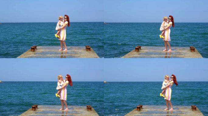 一个女人在海边的码头上抱着一个女孩