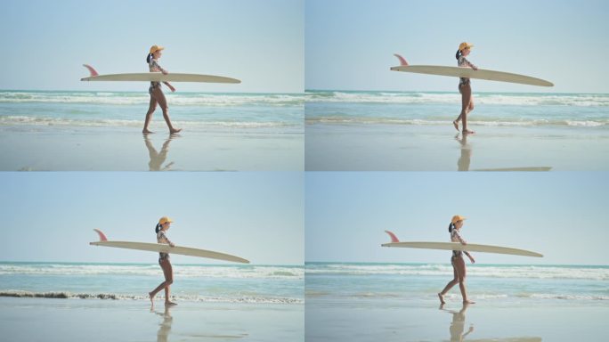 女冲浪者带着冲浪板在沙滩上行走，慢动作