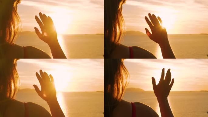 特写，镜头光晕:女性的手在亚得里亚海金色的夕阳下挥手