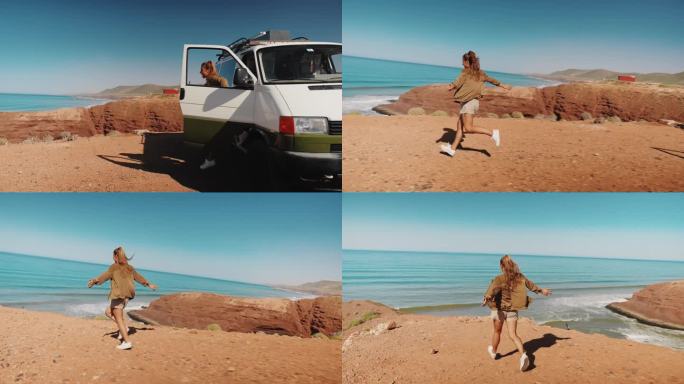 一名年轻女子离开一辆露营车，在沙滩上向海边跑去