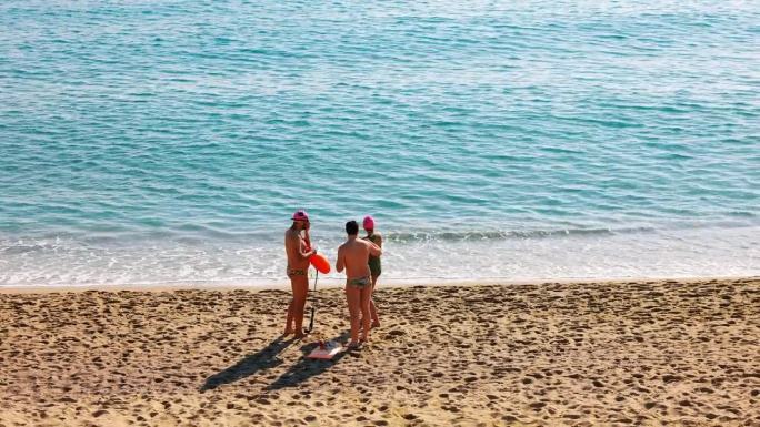 三个人在巴塞罗那海滩上穿着泳装