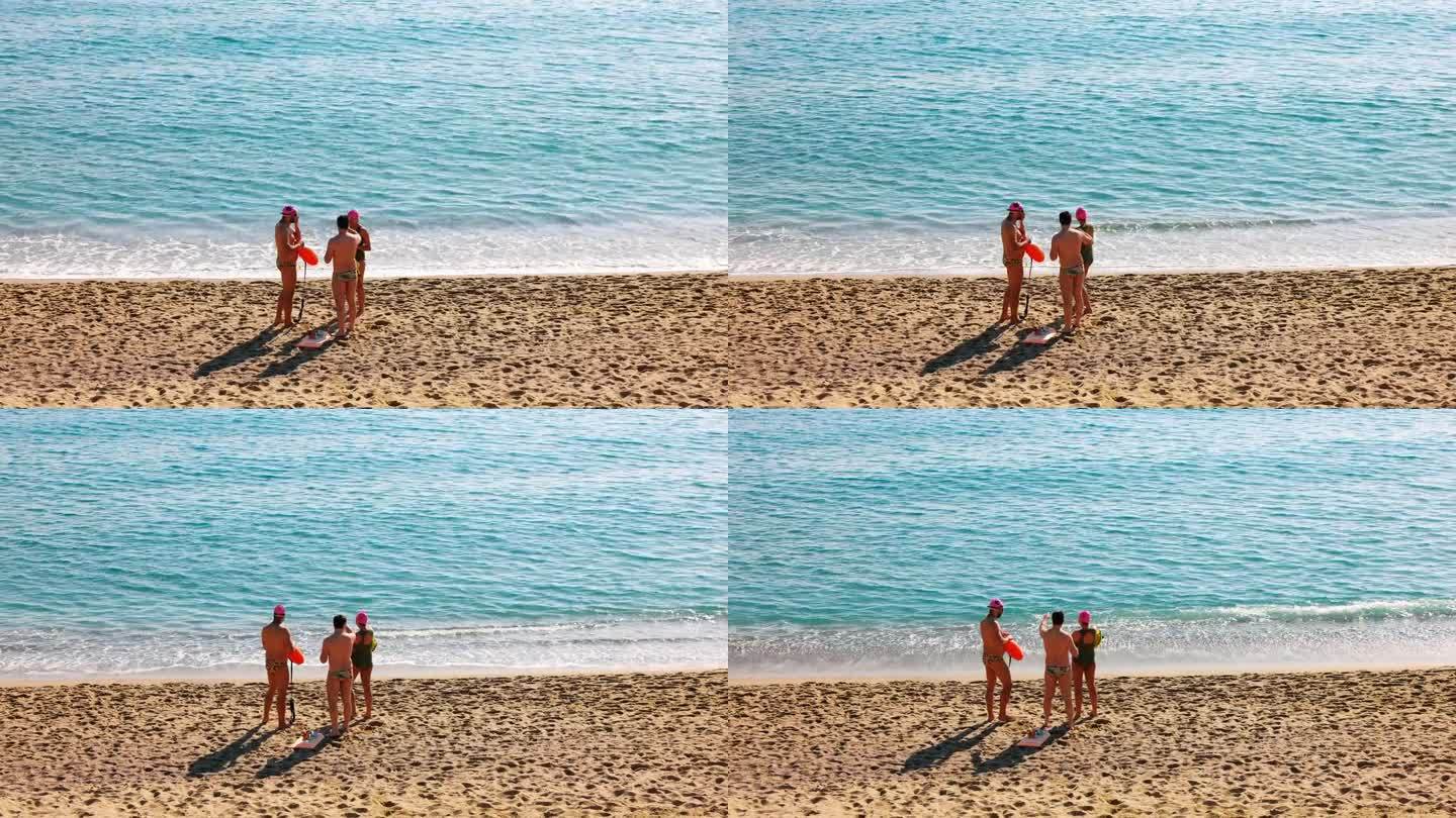 三个人在巴塞罗那海滩上穿着泳装
