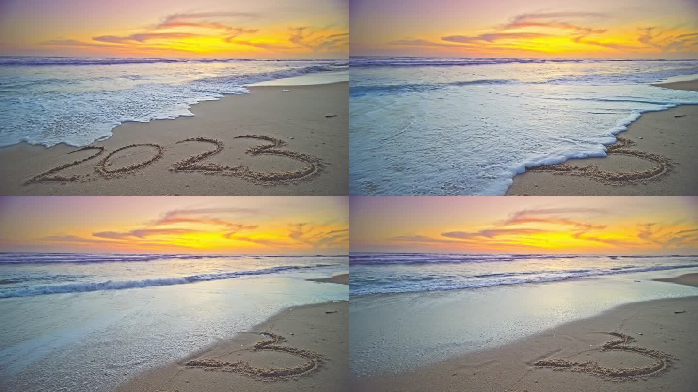 手绘数字2023文字在沙滩上，海洋日出或日落光在海滩岸边，金色的天空大海日落美丽的海滩背景