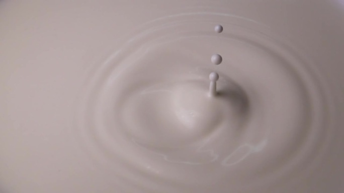 牛奶从顶部滴到中间的硬表面上的牛奶特写