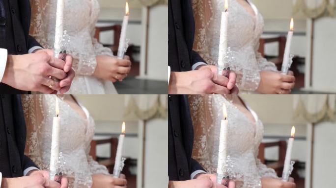 在教堂举行的婚礼上，新娘和新郎手持燃烧的蜡烛。教堂婚礼传统。