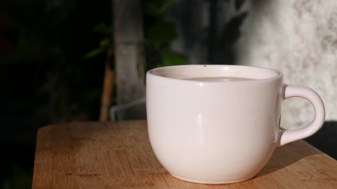 桌上的茶:一大杯茶在阳光下散发出美丽的热气。热气腾腾的杯子。在后院喝一杯热气腾腾的茶。烈日下热气腾腾