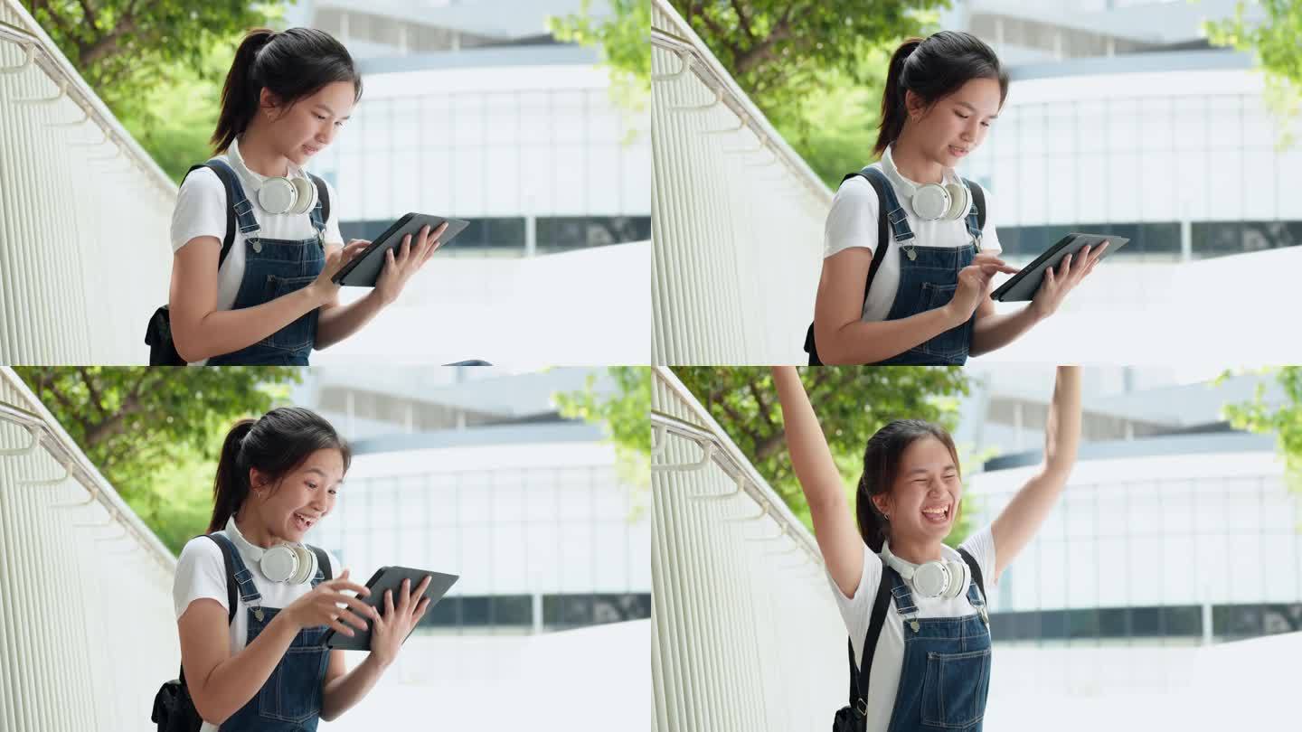 亚洲少女用平板电脑在线查看考试成绩，高考成功后兴奋的女孩开心。