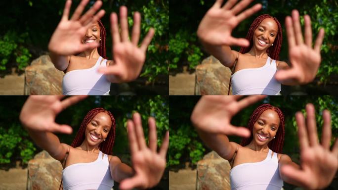 户外写真自然美丽的年轻非洲裔美国妇女红辫子发型，完美的白色牙齿微笑，笑着用手在阳光明媚的夏日与绿色的