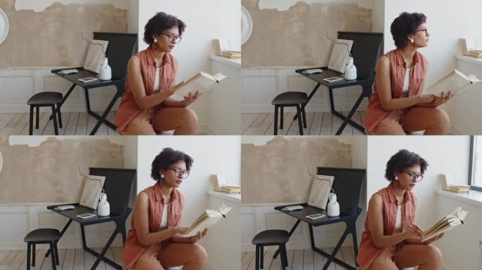 年轻的黑人妇女在时髦的公寓里读书
