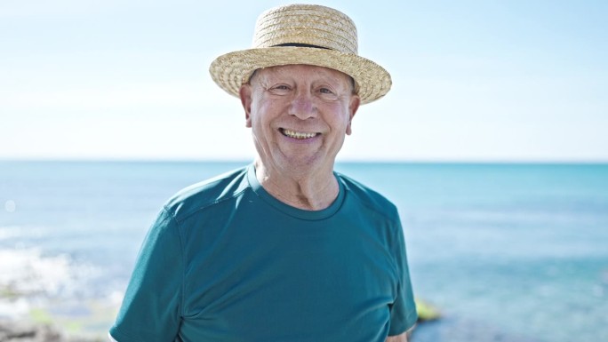 戴着夏日帽的白发老人在海边微笑