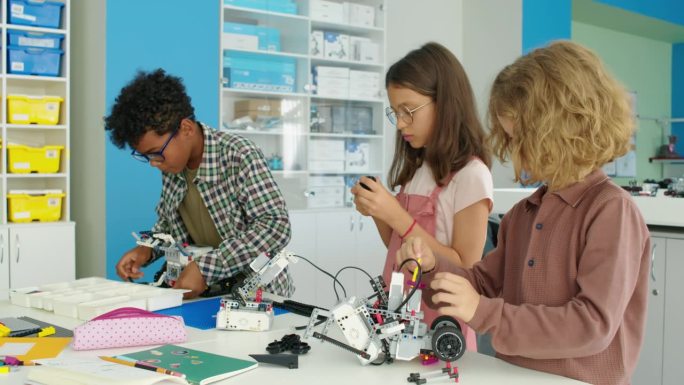 不同的孩子们在业余爱好俱乐部制作电动机器人模型