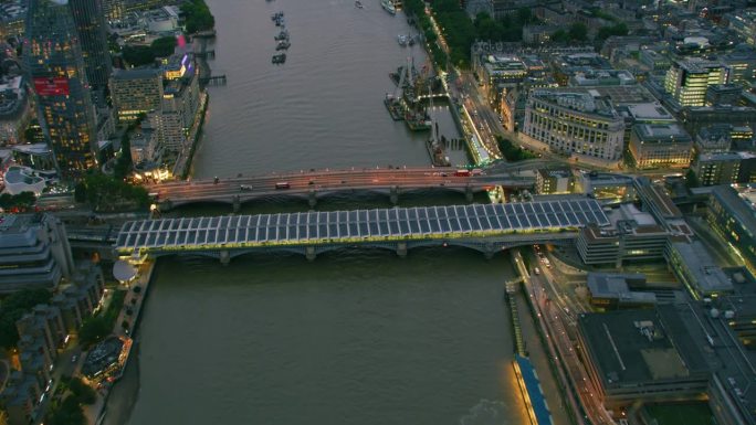 泰晤士河上伦敦著名桥梁的鸟瞰图。几艘船在河上航行，桥上挤满了人。城市的天际线。英格兰。英国。用红色武