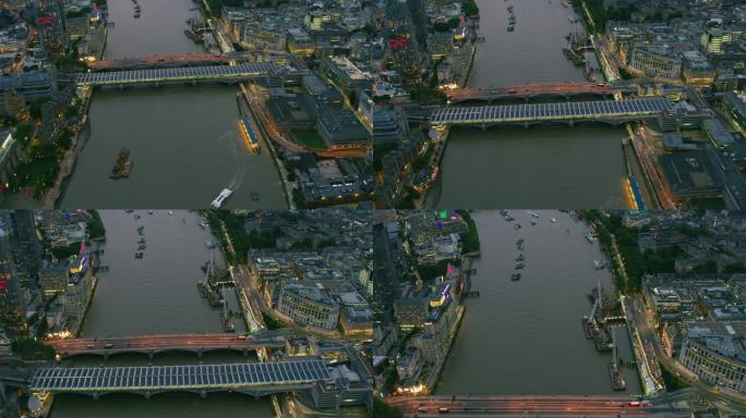 泰晤士河上伦敦著名桥梁的鸟瞰图。几艘船在河上航行，桥上挤满了人。城市的天际线。英格兰。英国。用红色武