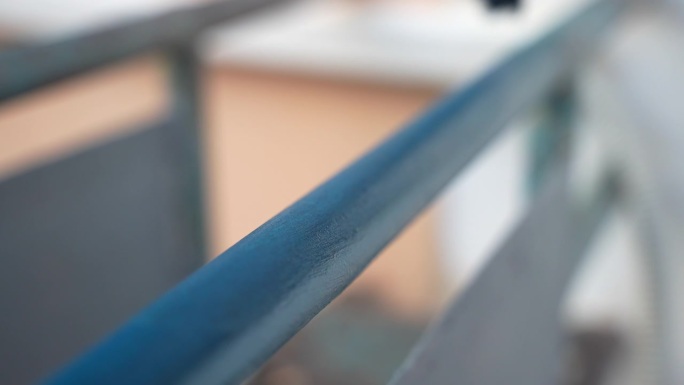 装修后的阳台框架的特写镜头，涂上了保护性的蓝色，修理人员戴着手套，用油漆刷在金属表面涂上了特殊的化学