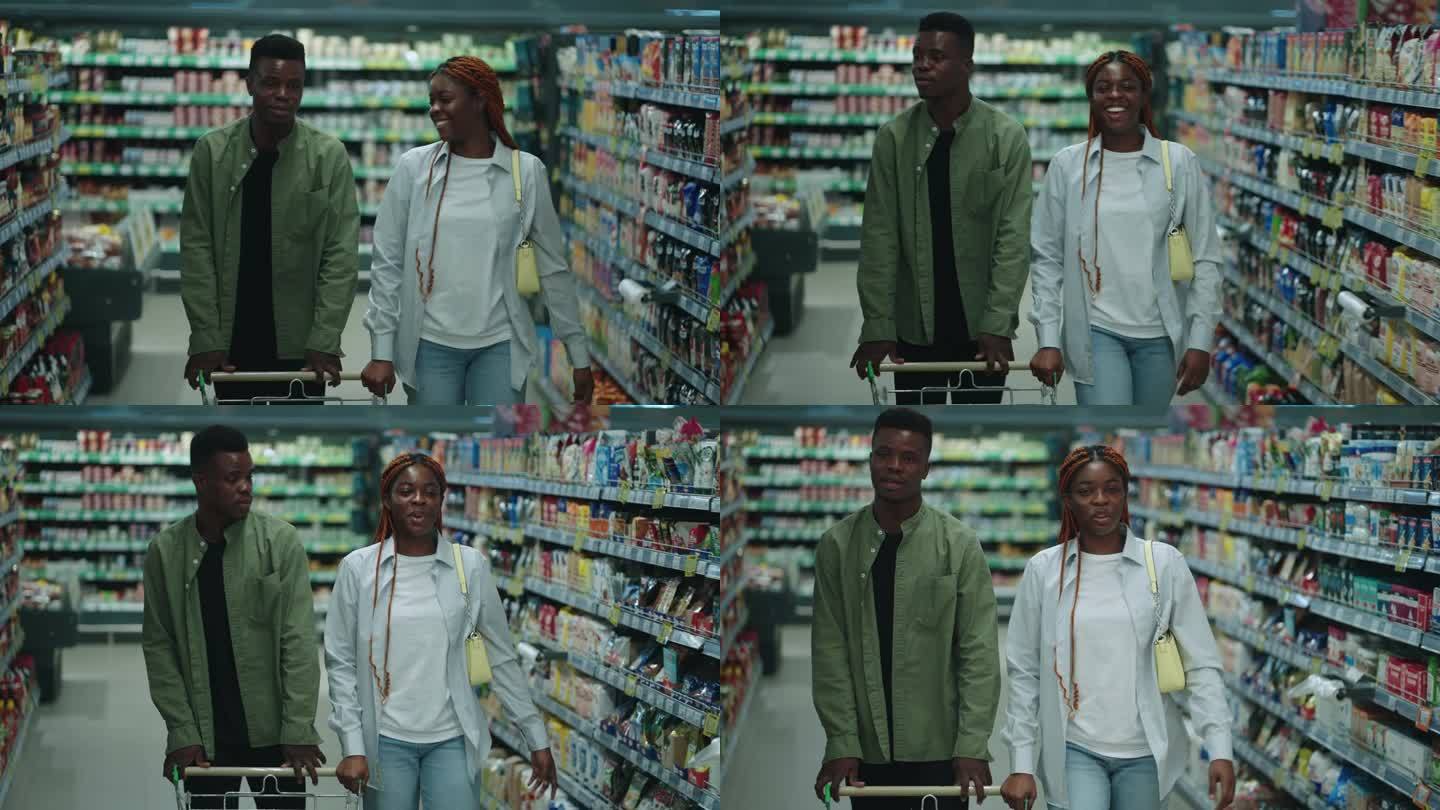 一对黑人夫妇走在超市的过道上愉快地聊天。男伴侣推着车，女伴侣买东西