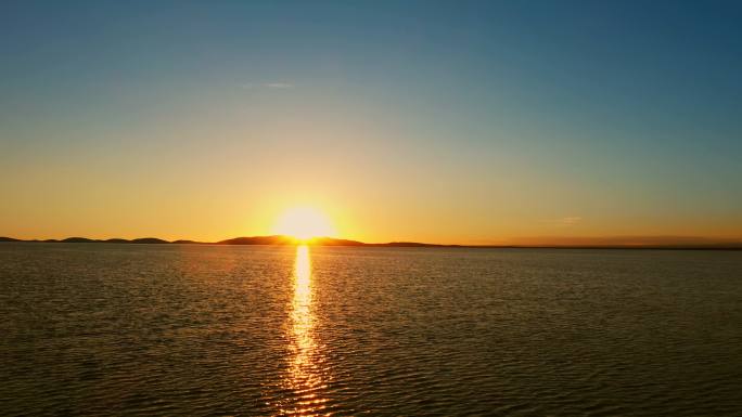 航拍湖边的落日、夕阳下的蓝色湖水、青海湖