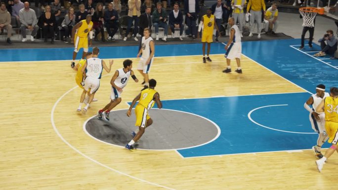 篮球赛在竞技场上的慢动作回放。黄队在队友之间传球，前锋从远处得分两分。体育电视频道播放回放