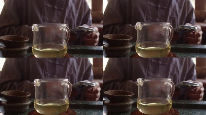 茶艺大师使用智能手机在茶道上等待整个茶水冷却。