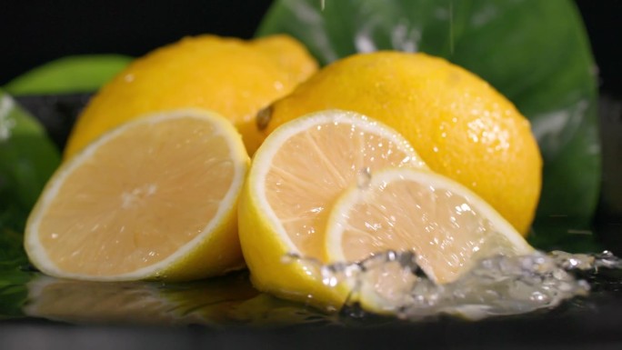 多汁的柠檬和诱人的果肉在水倒在一个黑暗的背景，特写
