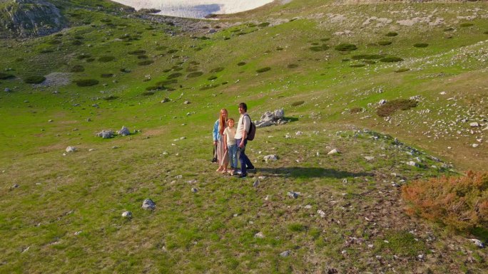 一个年轻的家庭用无人机拍摄了他们的户外冒险。父亲，母亲和他们的儿子站在一个令人惊叹的山谷中，背景是白