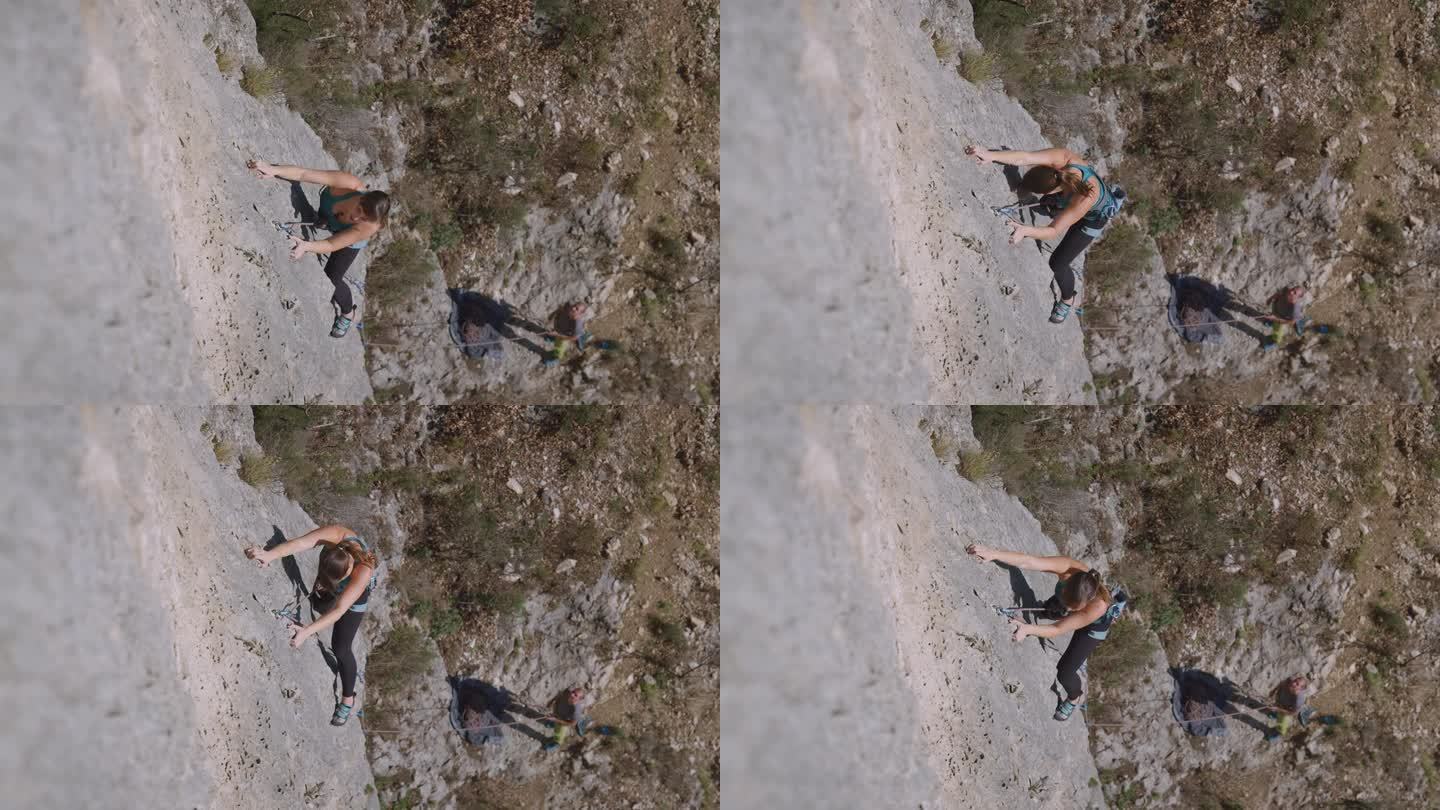 自上而下:年轻的女攀岩者在保护绳上爬上石灰岩攀岩墙