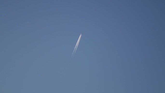 日落时分，一架飞行中的客机划过蓝天的轨迹。凝结尾迹或蒸汽尾迹是飞机发动机排气产生的线状云。克罗地亚罗