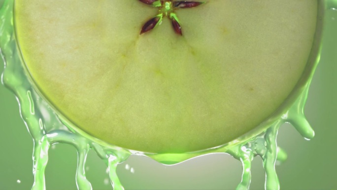 流动的青苹果汁从苹果切片，微距镜头在慢动作