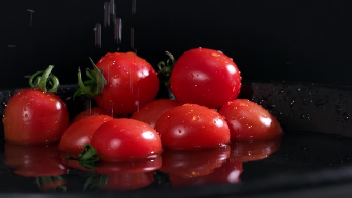 蔬菜收获，成熟的西红柿落入水中在黑暗的背景，溅在慢镜头，特写