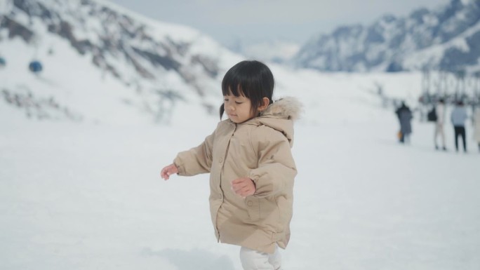 可爱的小女孩走在雪地上，跌倒，然后站起来。