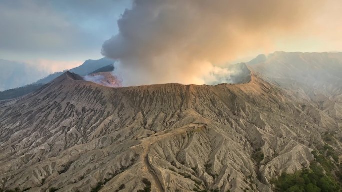 空中无人机拍摄的火山喷发日落场景，被云、雾和烟包围的Bromo火山与塞默鲁山、Batok和Widod
