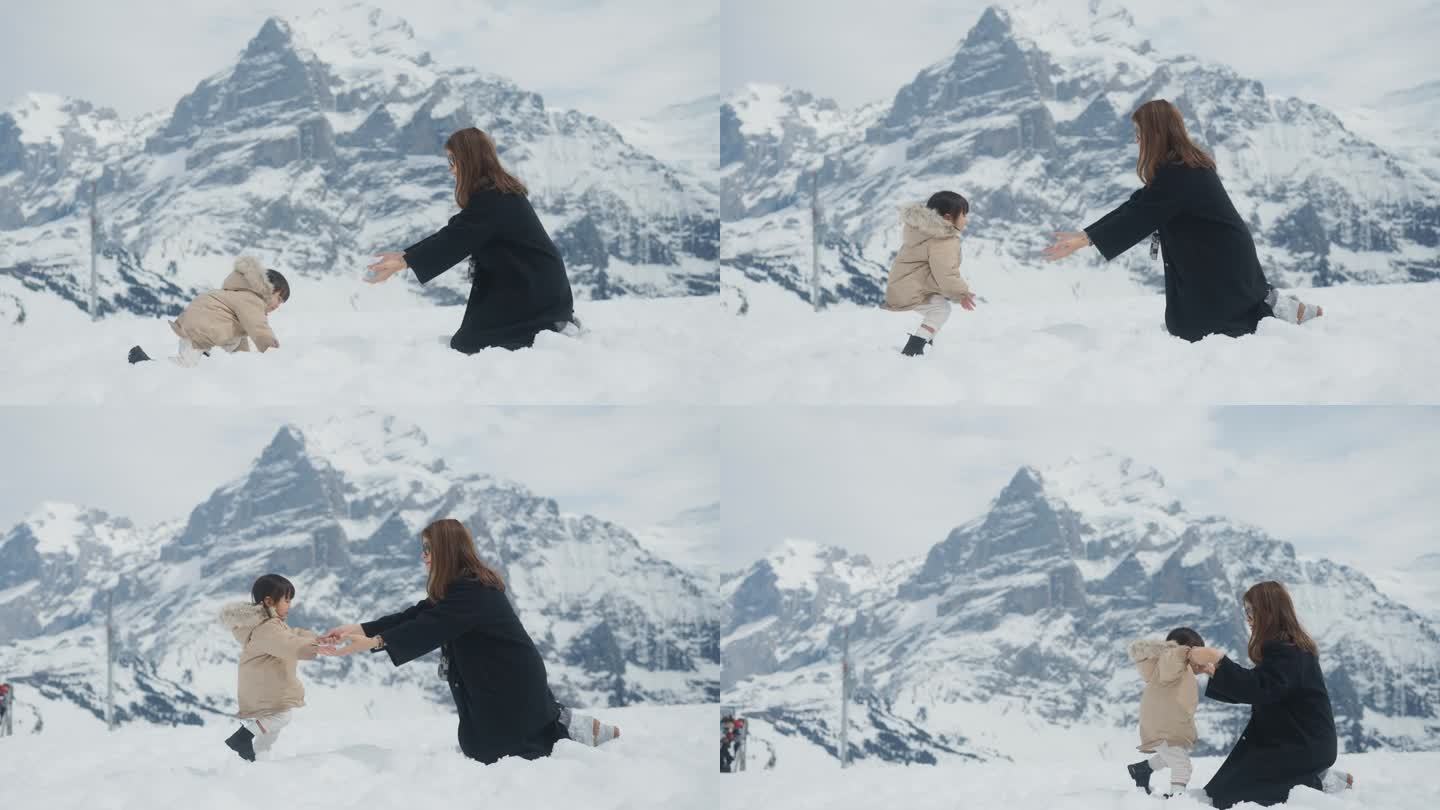 快乐的女婴试图站在雪地上，走着拥抱她的妈妈。
