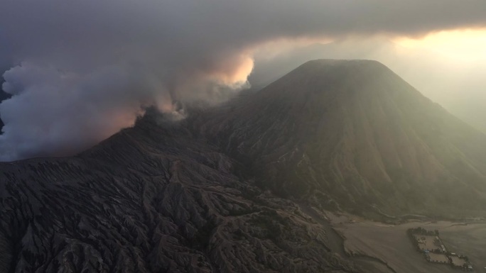 空中无人机拍摄的火山喷发日落场景，被云、雾和烟包围的Bromo火山与塞默鲁山、Batok和Widod