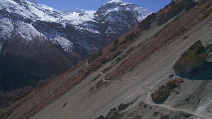 空中接近放大视野的驴车和夏尔巴人在通往高喜马拉雅山脉蒂利科大本营的路上。安纳普尔纳环行。旅游和徒步旅