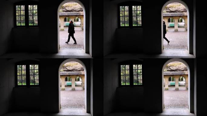 一个女人走在有门有窗的教堂天井里