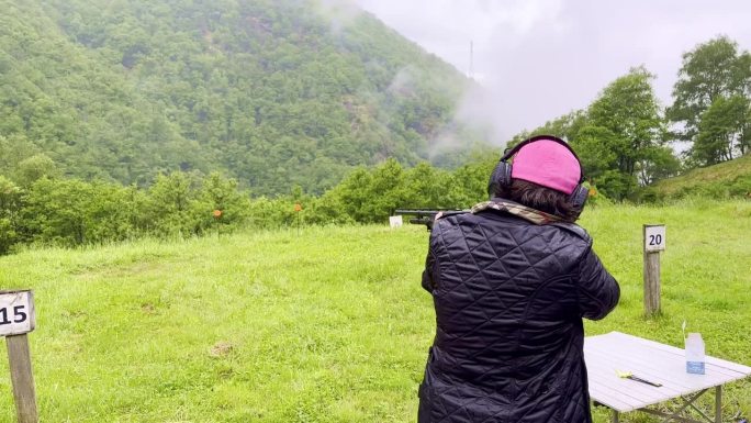 女子在室外射击场用猎枪进行双向飞碟射击